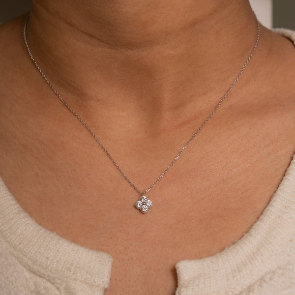 Silver necklace with a small pendant on a person wearing a beige top.
