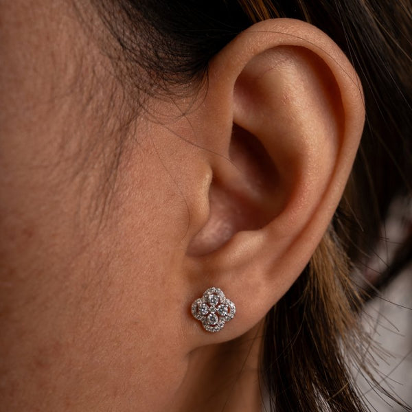 Close-up of an ear wearing a diamond earring with a blurred background