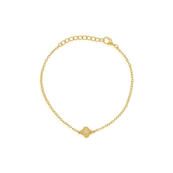 Gold bracelet with a small clover element on a white background