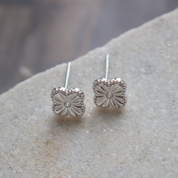 Silver clover earrings on a stone surface