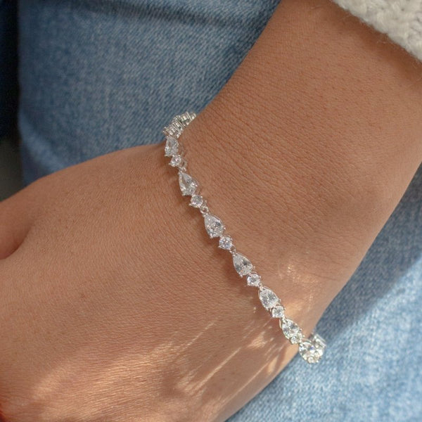 Silver bracelet with clear stones on a wrist against a denim background