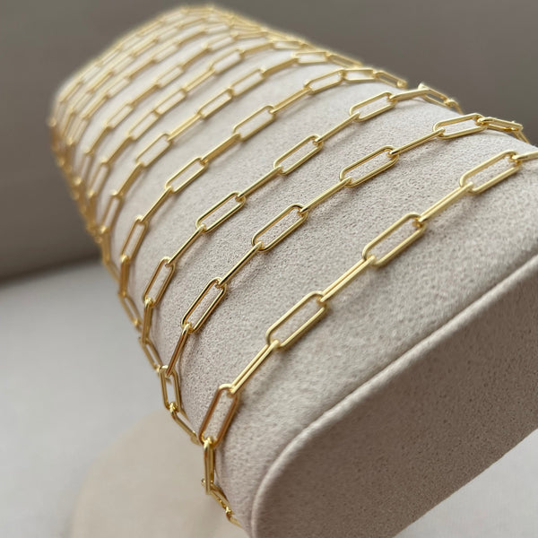 Stack of gold bracelets on a white stand with a neutral background
