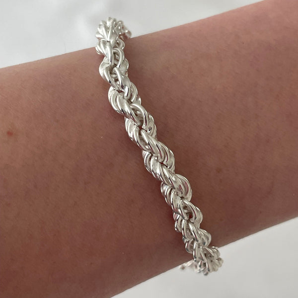 Silver braided bracelet on a wrist against a white background