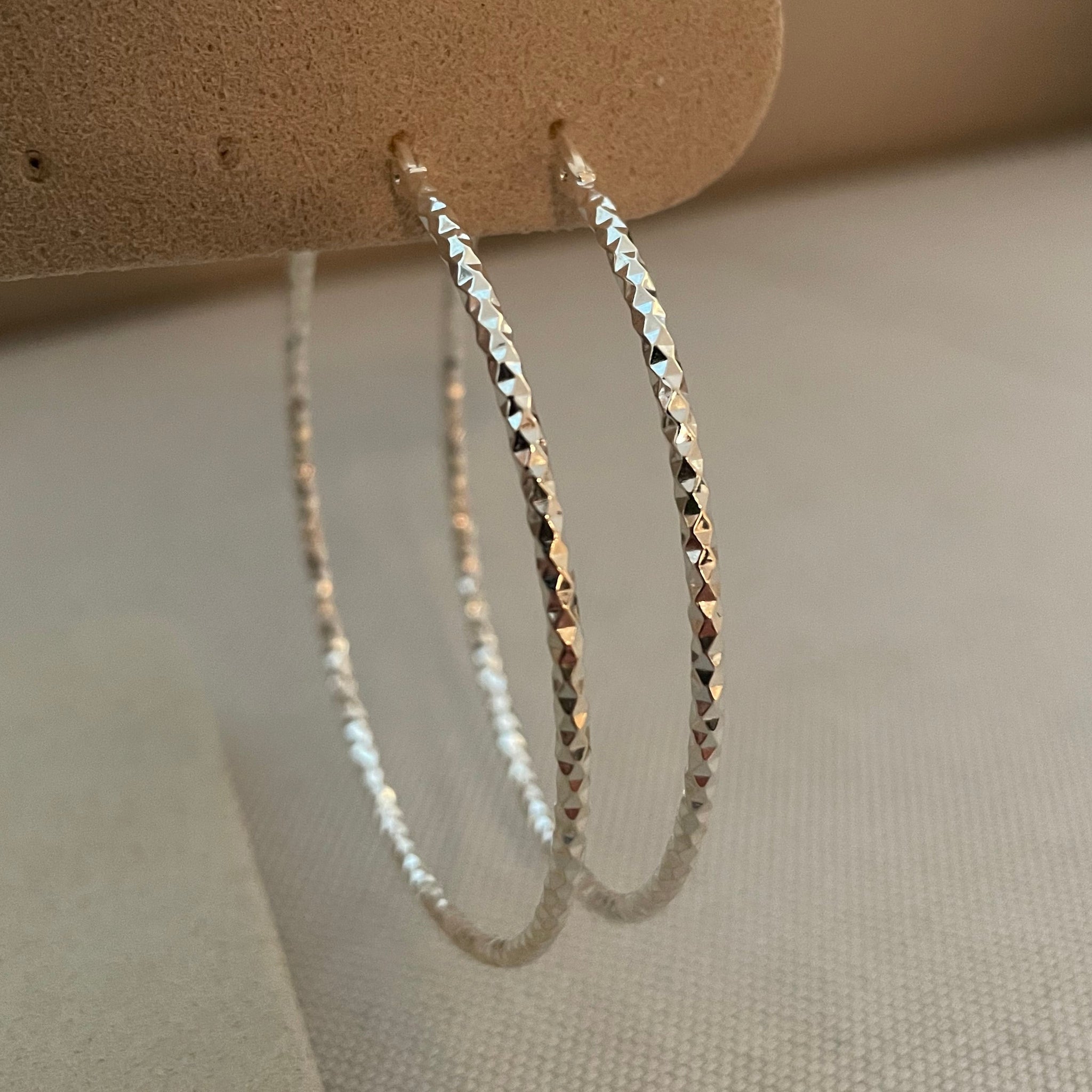 Silver bracelet on a beige stand with a neutral background