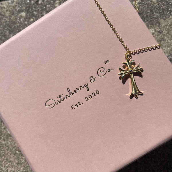 Vintage gold cross necklace on top of blush pink Sisterberry & Co. jewellery box