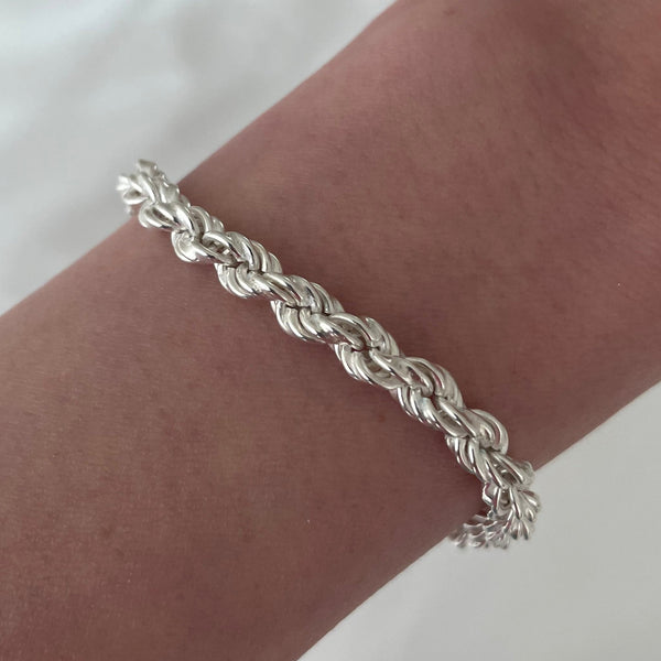 Silver braided bracelet on a wrist with a blurred background
