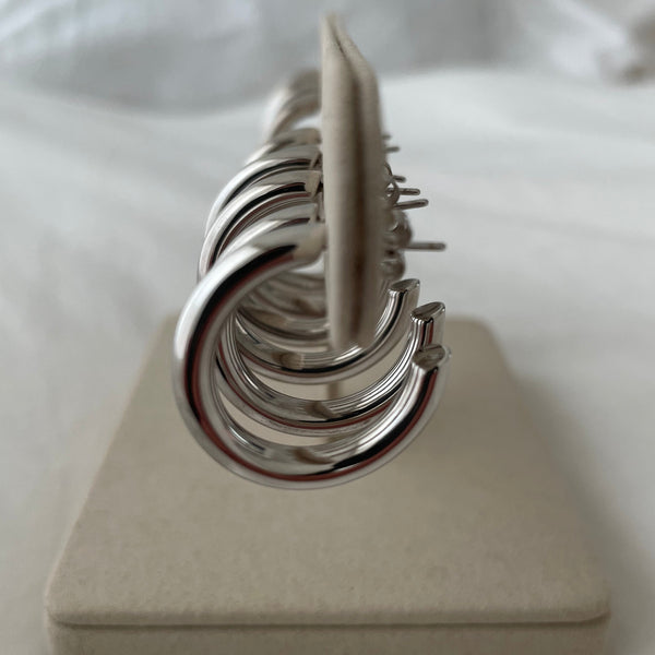 Side view of Row of sterling silver hoop earrings on jewellery stand