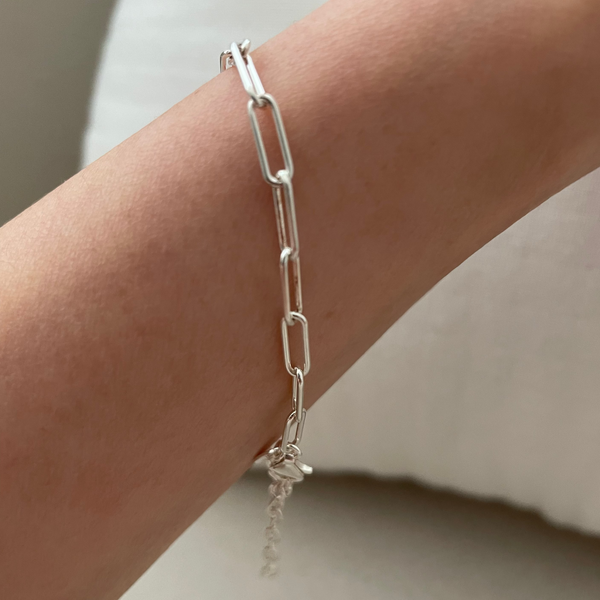 Silver chain bracelet on a wrist with a neutral background