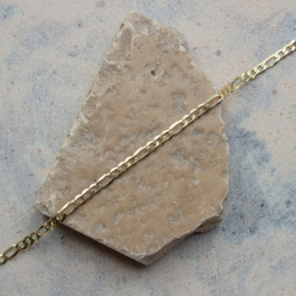 Gold chain necklace on a stone surface