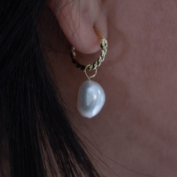 Pearl earring on a person's ear with a blurred background