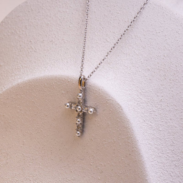 Silver cross necklace with pearls on a white background