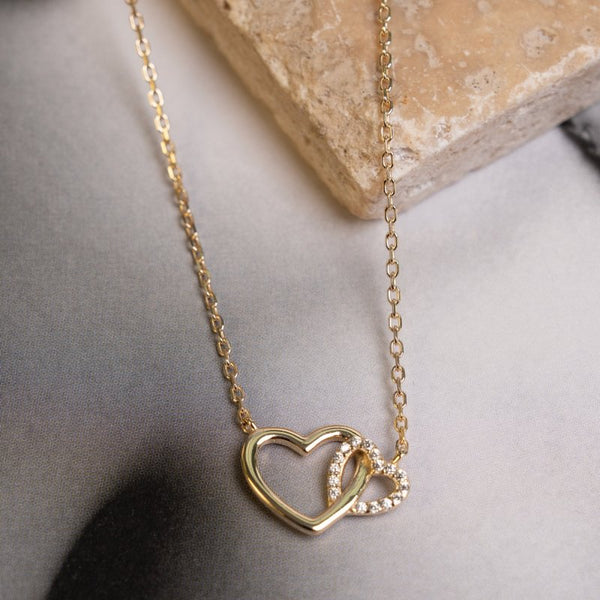 Gold heart-shaped necklace on a neutral background