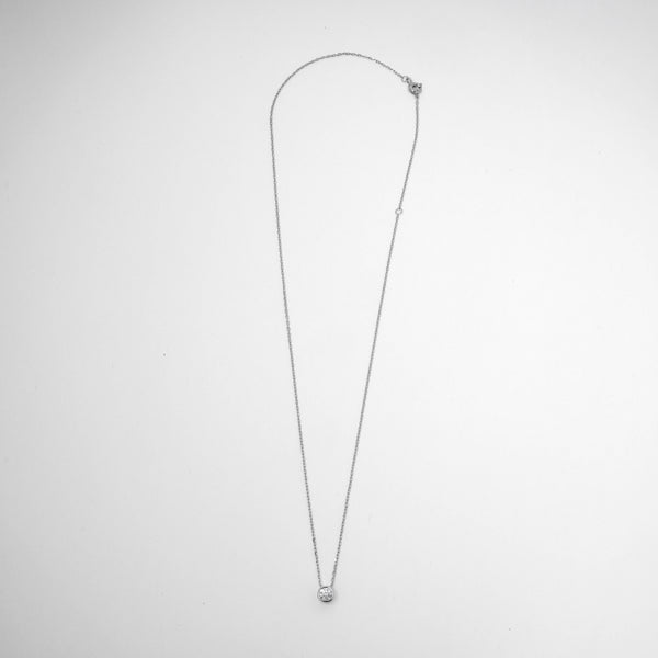 Silver necklace with a small round diamond bezel pendant on a white background