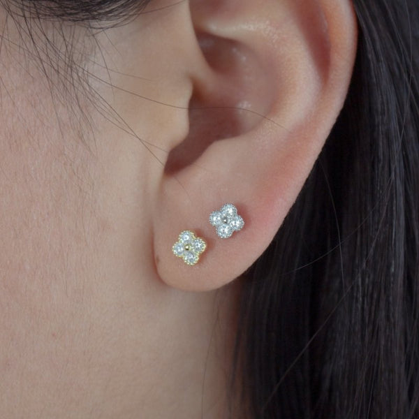 Close-up of a person's ear wearing two diamond stud earrings.