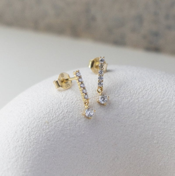 Gold earrings with clear stones on a white surface