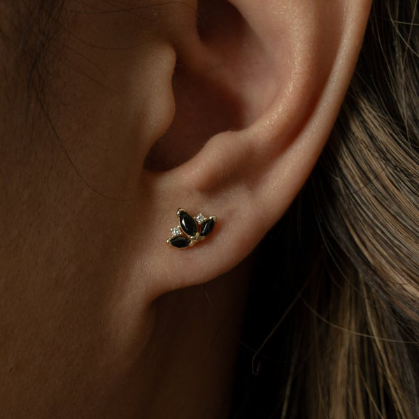 Close-up of an ear wearing a gold and black earring.